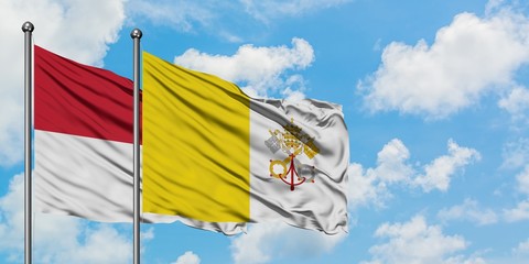 Iraq and Vatican City flag waving in the wind against white cloudy blue sky together. Diplomacy concept, international relations.