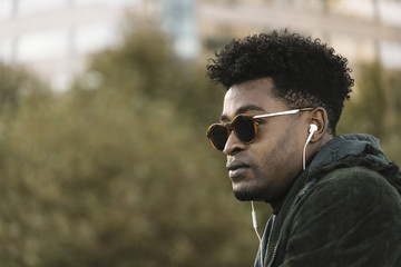 black man with jacket and sunglasses listen music