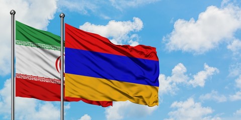 Iran and Armenia flag waving in the wind against white cloudy blue sky together. Diplomacy concept, international relations.