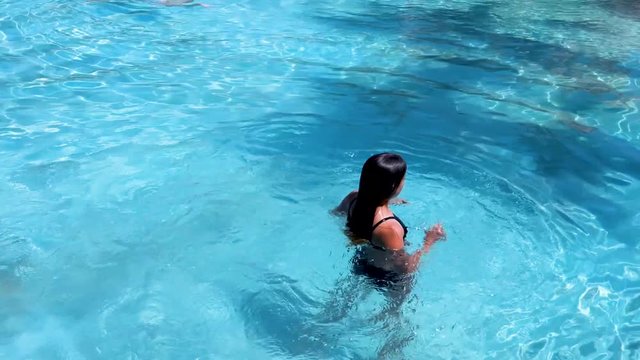 Pretty athletic sun tanned girl tumbling under water in a swimming pool on vacation - for Beauty and Body care, Sports, Health, Fitness