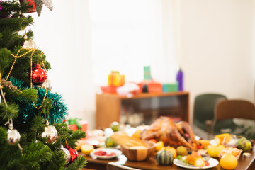 Christmas tree with decoration over table of food and turkey for thanksgiving dinner, blur background