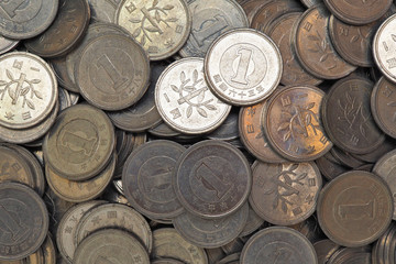 Heap of Japanese coins at 1 yen. News about the economy, finances and interest rate of the central bank of Japan. External and public debt, deflation. View from above. Close-up