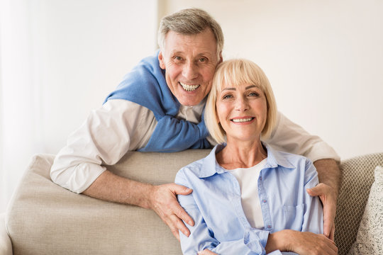 Lovely mature man embracing wife and smiling to camera