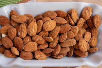 Raw almond or prunus dulcis with skin on white tray.