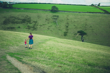 Young mother and toddler walking in field