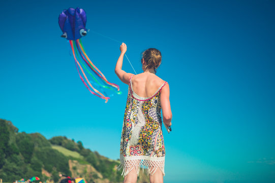 Young woman flying kite on beach in summer