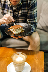 Man eat tiramisu cake near table 