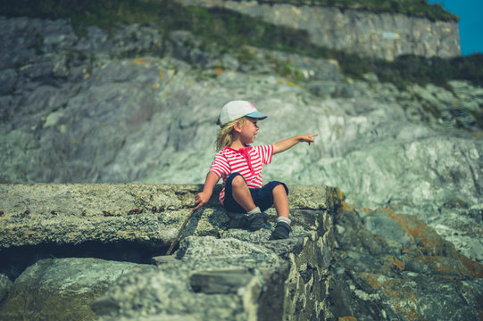 Little toddler sitting on a rock by the sea