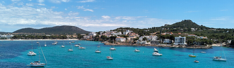 Fototapeta na wymiar Panoramic image coastline of Santa Ponsa town in the south-west of Majorca Island. Located in the municipality of Calvia, moored yachts on the turquoise tranquil bay of Mediterranean Sea, Spain