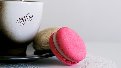 Colorful macaroons and cup of coffee on white background