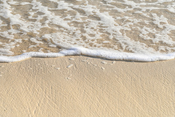 frothy ocean water edge on tropical beach sand