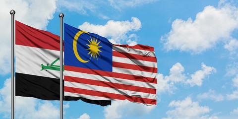 Iraq and Malaysia flag waving in the wind against white cloudy blue sky together. Diplomacy...