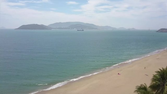 A flying camera captures a sea wave on a sandy beach in Vietnam.