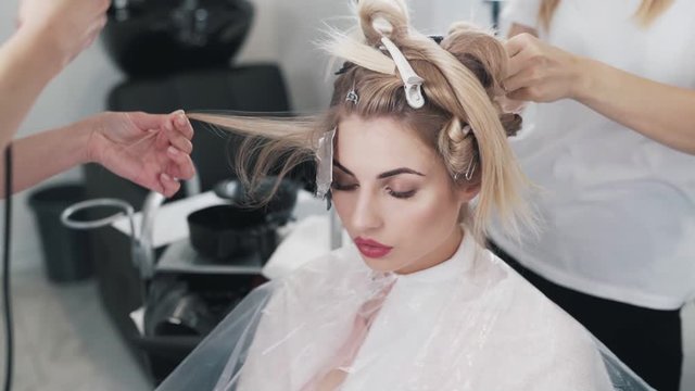 Close up, hairdressers do hair coloring for woman in beauty studio