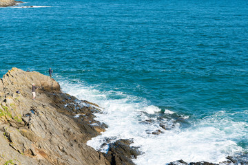 fishermen fishing on the rocky coast of Brittany in northern France