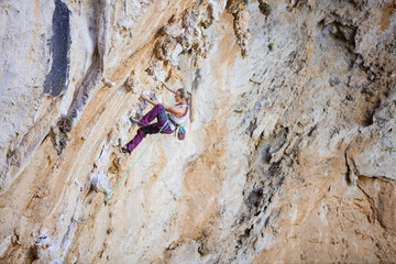 Female climber on challenging route of overhanging cliff