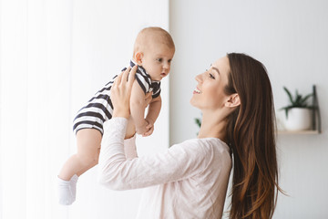 Millennial mom playing with her newborn baby at home