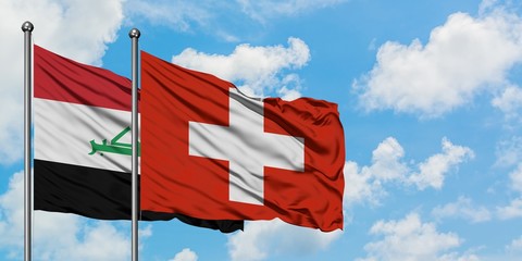 Iraq and Switzerland flag waving in the wind against white cloudy blue sky together. Diplomacy...
