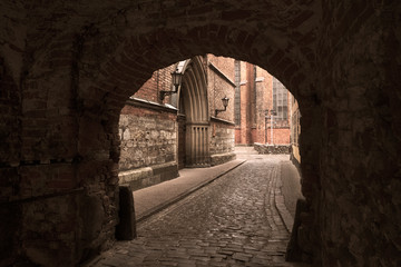  stone arch tunnel leads to a catholic temple. Riga city Latvia