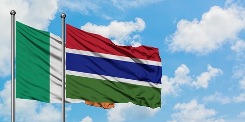 Ireland and Gambia flag waving in the wind against white cloudy blue sky together. Diplomacy concept, international relations.