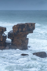 A huge ocean waves breaking on the coastal cliffs in at the cloudy stormy day. Breathtaking romantic seascape of ocean coastline. Peniche, Portugal.