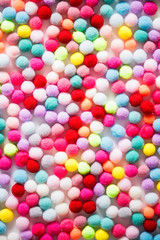 Texture of small colorful textile fluffy pompons on a white background. Flat lay. Creative.