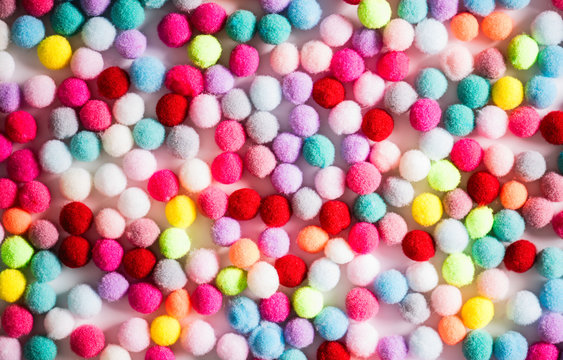 Texture of small colorful textile fluffy pompons on a white background. Flat lay. Creative.