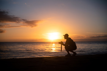 Obraz premium The silhouette of a male hobbyist photographer taking photos of a beautiful colorful sunset on the West Puerto Rico coast near Rincon