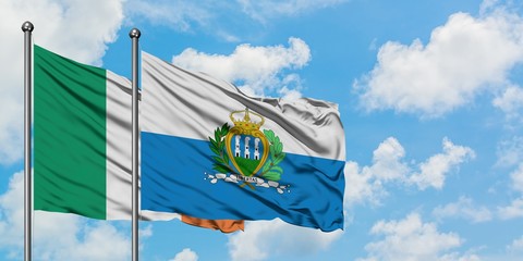 Ireland and San Marino flag waving in the wind against white cloudy blue sky together. Diplomacy concept, international relations.