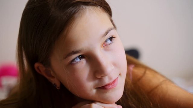 A young girl is lying and looking at the camera. Portrait of a young girl.