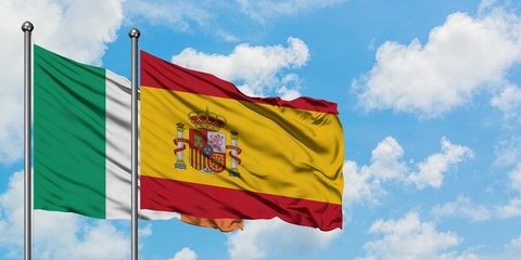 Ireland and Spain flag waving in the wind against white cloudy blue sky together. Diplomacy concept, international relations.