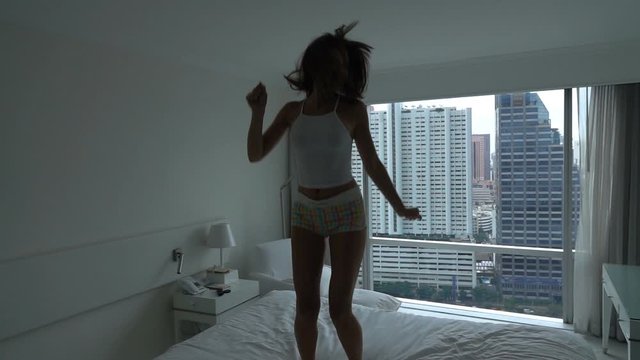 Happy excited sexy young woman jumping on bed, super slow motion, 240fps
