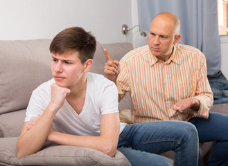 Father scolding his turned away son