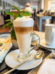Hot milk foamy with bitter coffee, cappuccino, in high glass for breakfast in restaurant