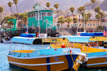 Colorful water taxi boats sit moored near the famous Green Pier at Avalon, on Catalina Island - obrazy, fototapety, plakaty