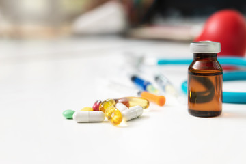Medicine, syringe, injection and stethoscope on a white wooden table. Medical and Health care or...