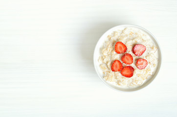 Fototapeta na wymiar Oatmeal porridge with strawberry slices in bowl