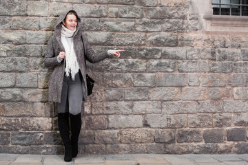 Fototapeta na wymiar cheerful female in coat hood near wall