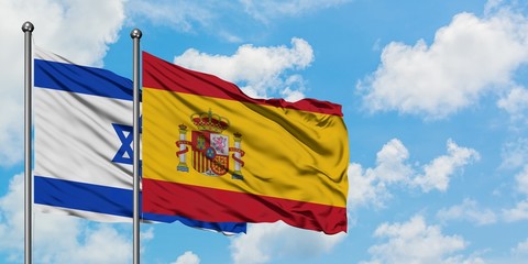 Israel and Spain flag waving in the wind against white cloudy blue sky together. Diplomacy concept, international relations.