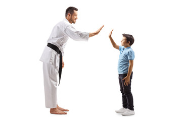 Man in karate kimono gesturing high-five with a boy