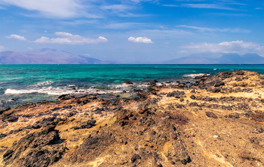Fototapeta na wymiar tranquillity and silence , abandoned beach with azure water, rocks on coast, beautiful turquoise sea with mild surf, deep blue sky with clouds and mountains on background, Mediterranean landscape