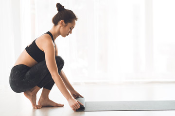Sporty woman rolling mat after yoga class