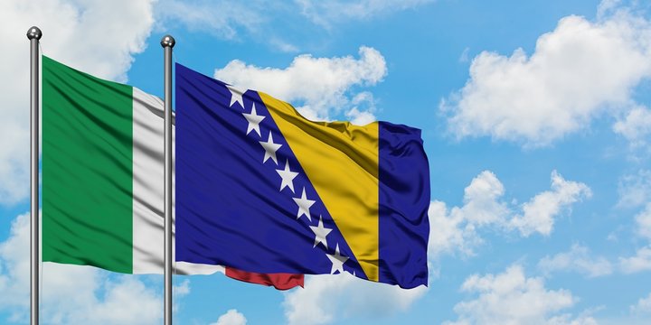 Italy and Bosnia Herzegovina flag waving in the wind against white cloudy blue sky together. Diplomacy concept, international relations.