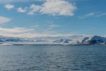 Snow covered mountains and a glacier by an arctic fjord in Svalbard