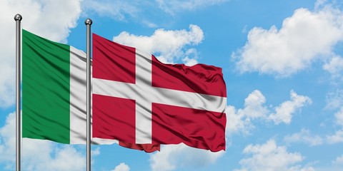 Italy and Denmark flag waving in the wind against white cloudy blue sky together. Diplomacy concept, international relations.
