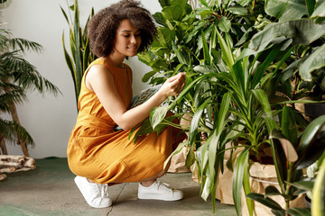 Beautiful brunette woman botanist working at her indoor garden  - obrazy, fototapety, plakaty