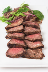 Plate with meat cutting and fresh greens on white plate