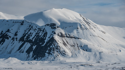 Fototapeta na wymiar Snowy mountains with avalanche tracks in the arctic