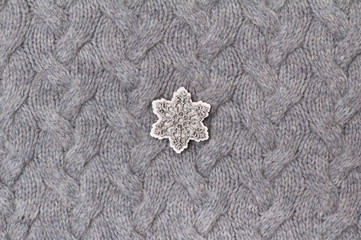 Texture of gray knitted fabric close up with wooden snowflake