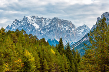 Colorful autumn forest and snow-capped mountain peaks of the Alps